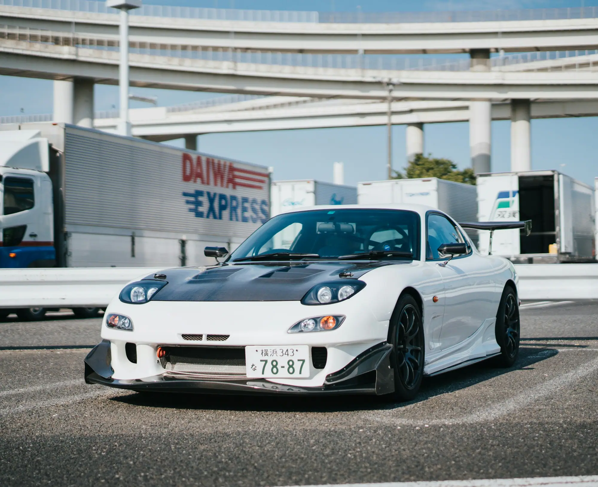 White Mazda RX-7 FD3S on Japanese plates near a freight terminal